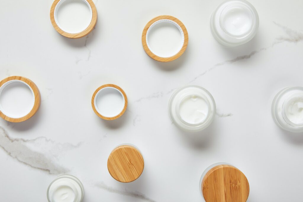 top view of jars with cosmetic cream on white surface