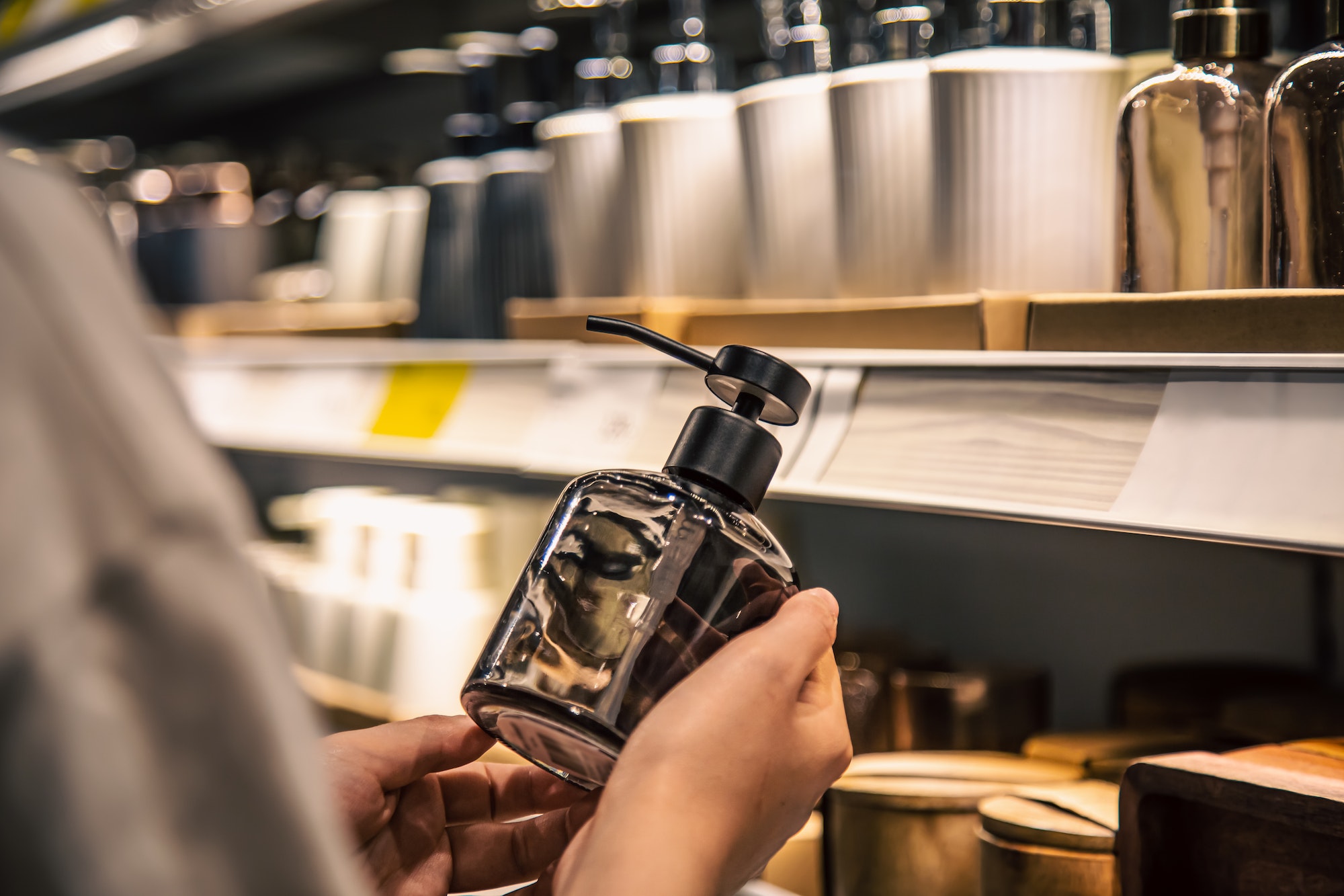 Close up, a dispenser for liquid soap in female hands in the store.