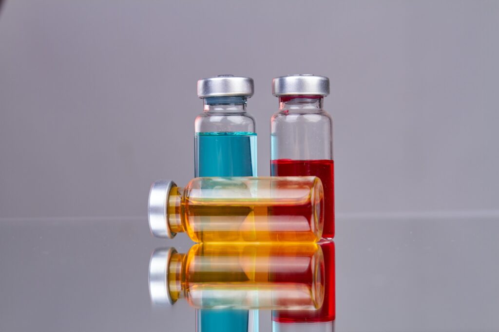 Collection of glass drug vials with colored medicine.