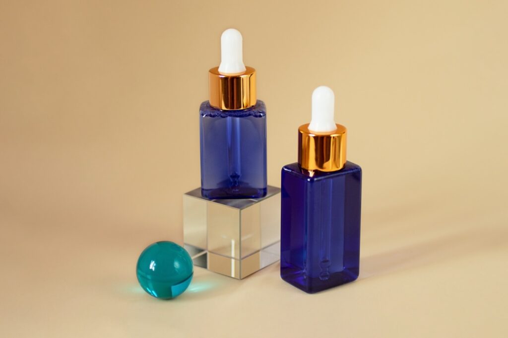 Cosmetics bottles with dropper in the glass podium.