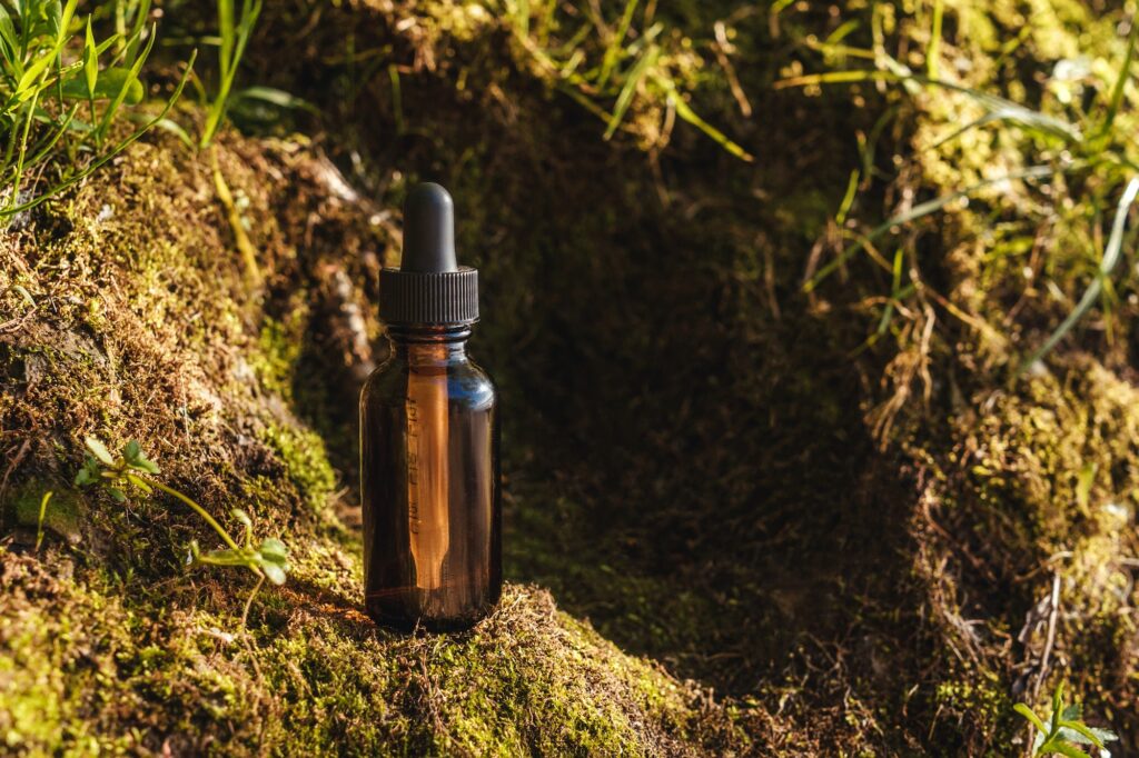 Glass cosmetic bottle with dropper on moss.