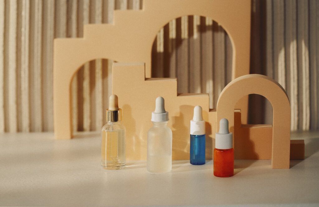 Glass dropper bottles with pipette on abstract trendy podium for cosmetics products