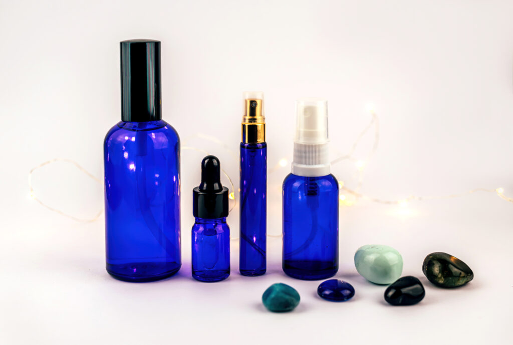 Blue bottles of different essential oils with gemstones on white background