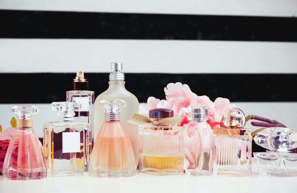 Bottles of perfume with flowers on white background