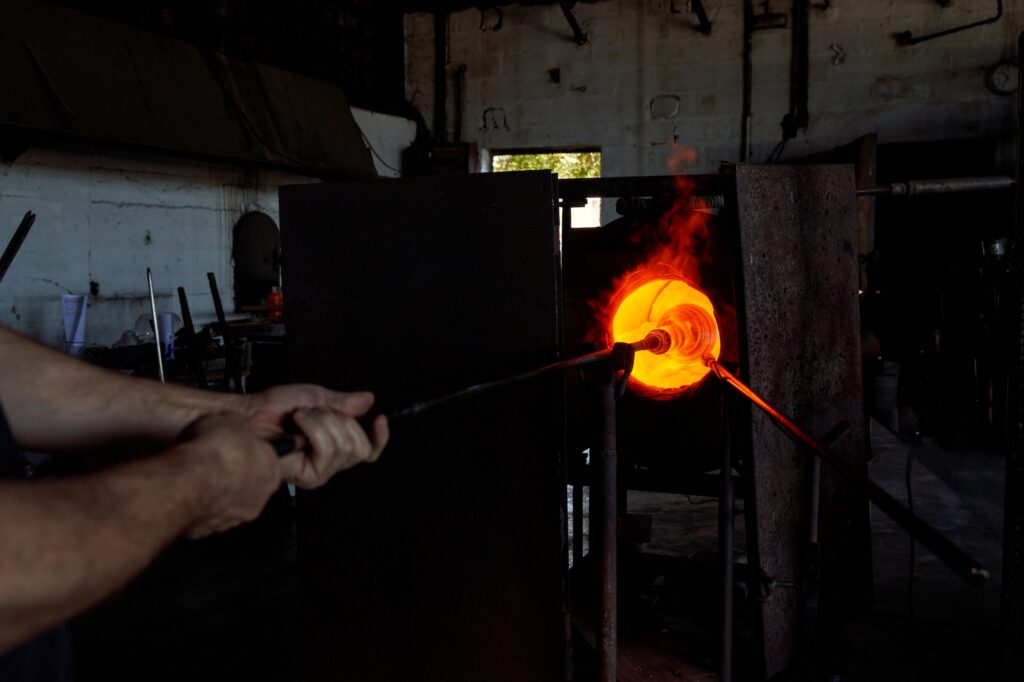 Crop craftsman putting liquid glass into annealer