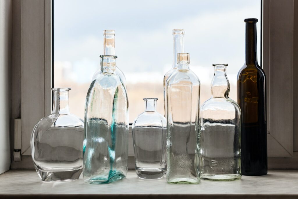 many empty bottles on windowsill and view of park