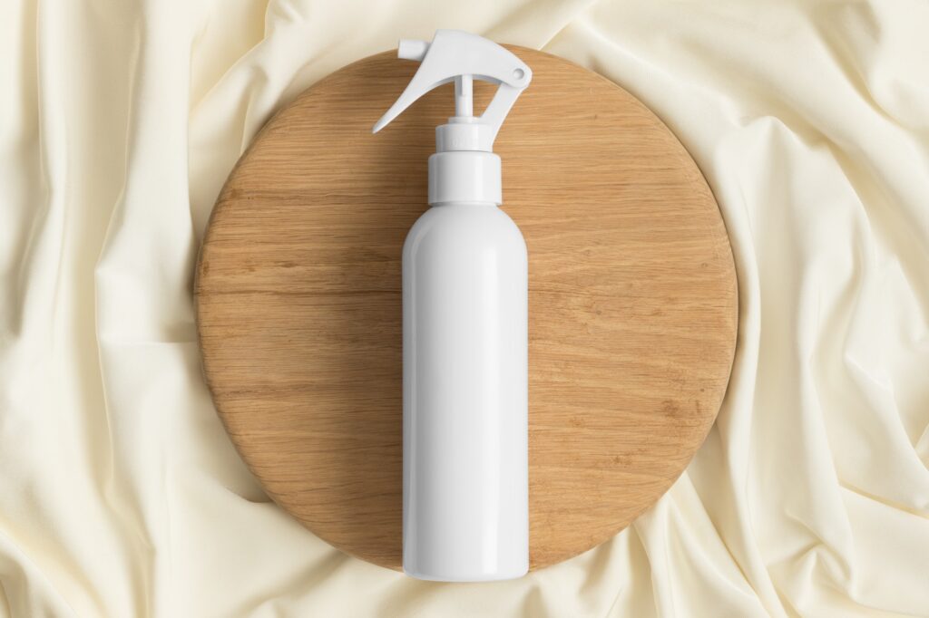 White cosmetic trigger sprayer bottle mockup on the yellow textile.