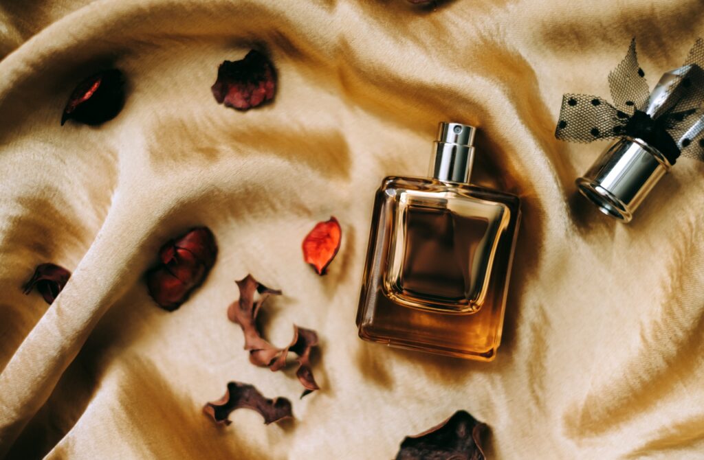 Cologne bottle on golden satin fabric with dried flower petals