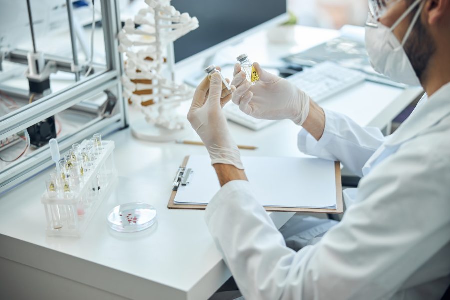 Man in a protective mask holding glass vials